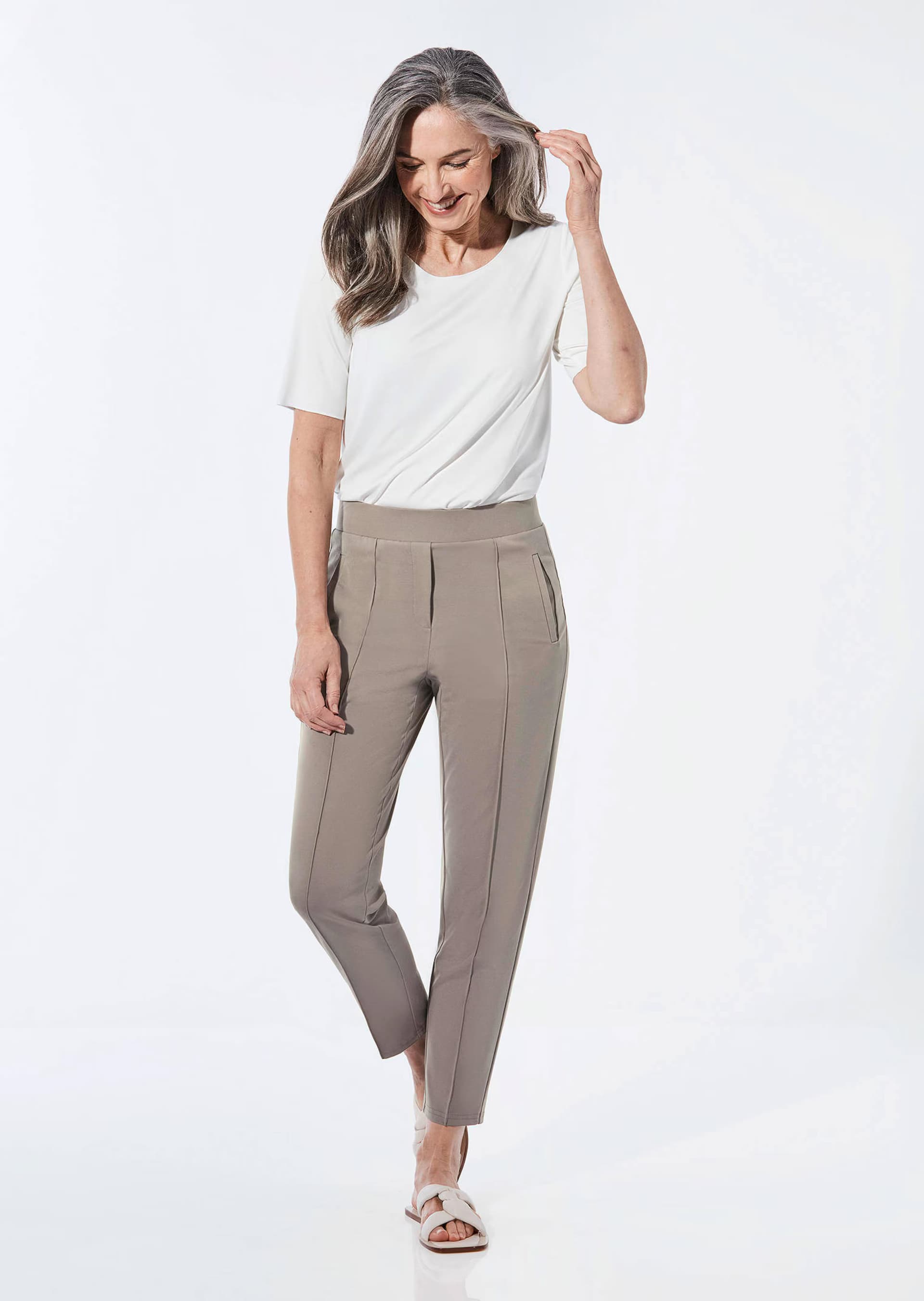 Mature woman wearing white shirt with taupe trousers